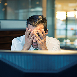 Guy holding head at computer