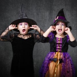 Two girls dressed for Halloween with fingers in ears