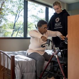Occupational therapist showing woman get out of bed with a walker