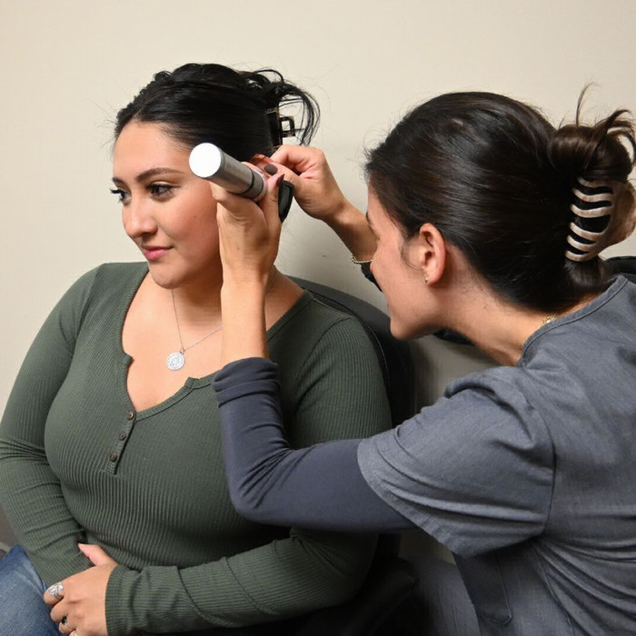 audiology student looking in a patient's ear