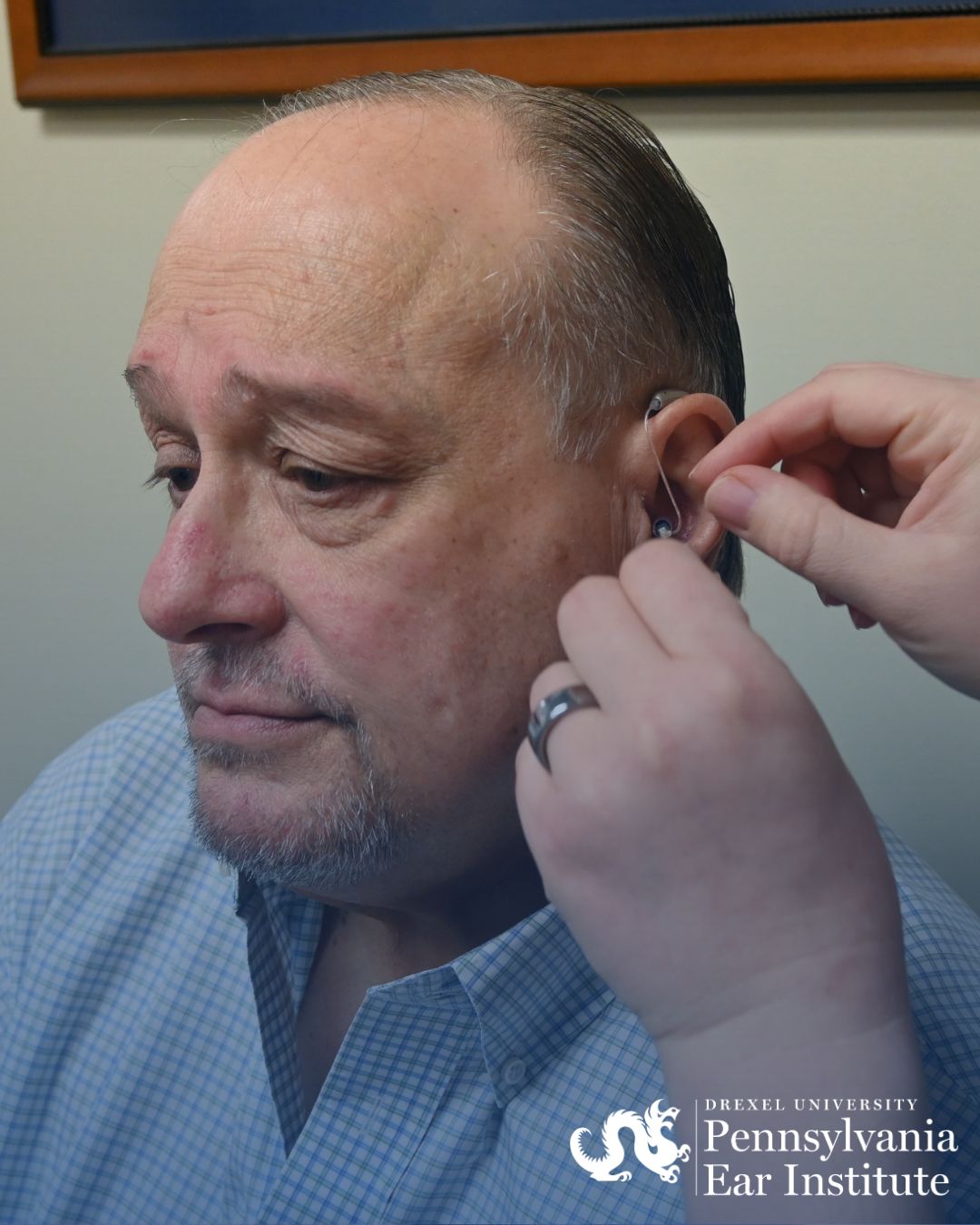 close up of hearing aid being placed in man's ear