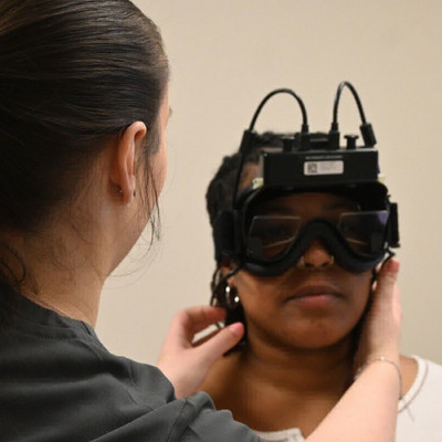audiologist putting goggles on patient during vestibular testing