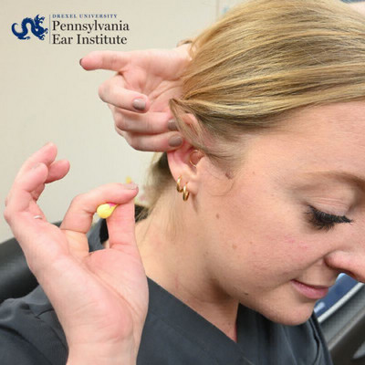 woman putting ear plug in her ear