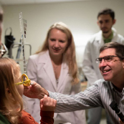optometrist and students conducting eye exam on child
