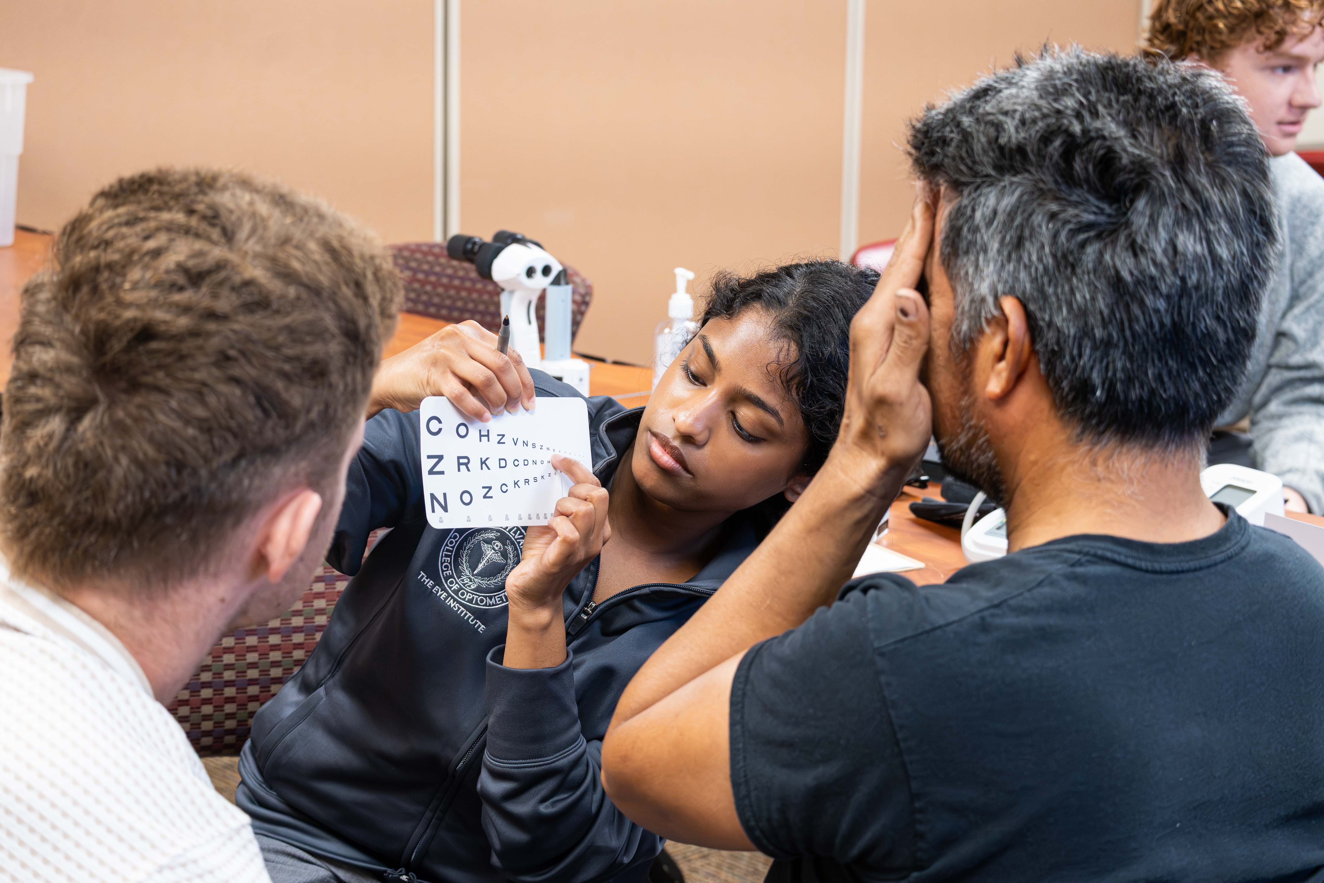 Student helps patient with eye exam