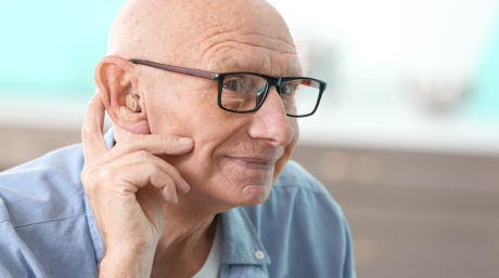 Elderly man with glasses wearing a hearing aid