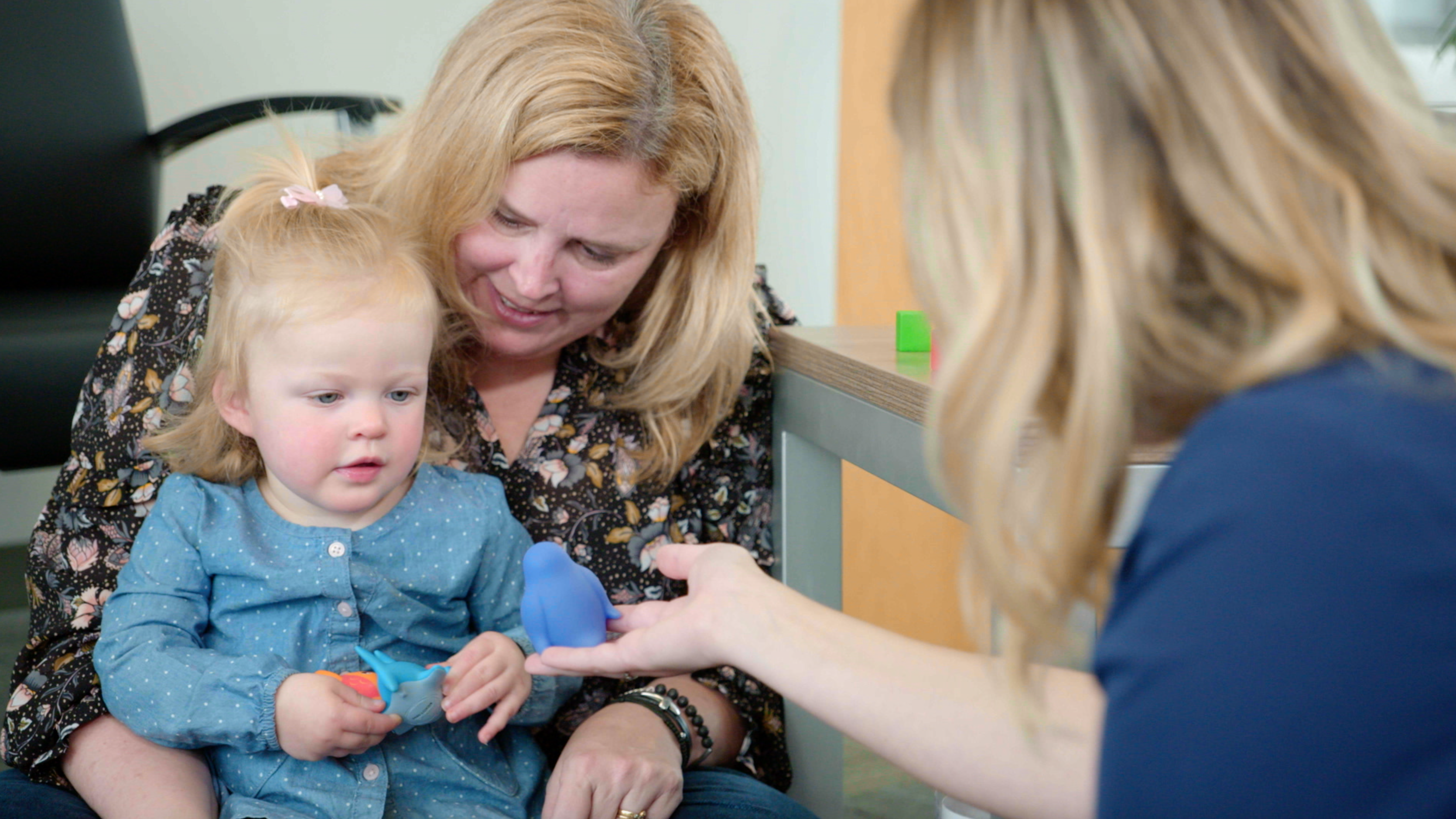 woman holding toddler playing with block