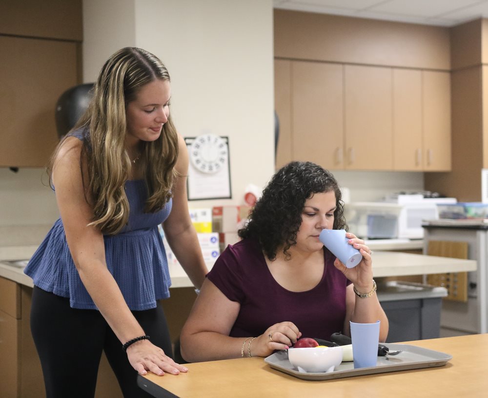 SLI student with client working on swallowing exercises